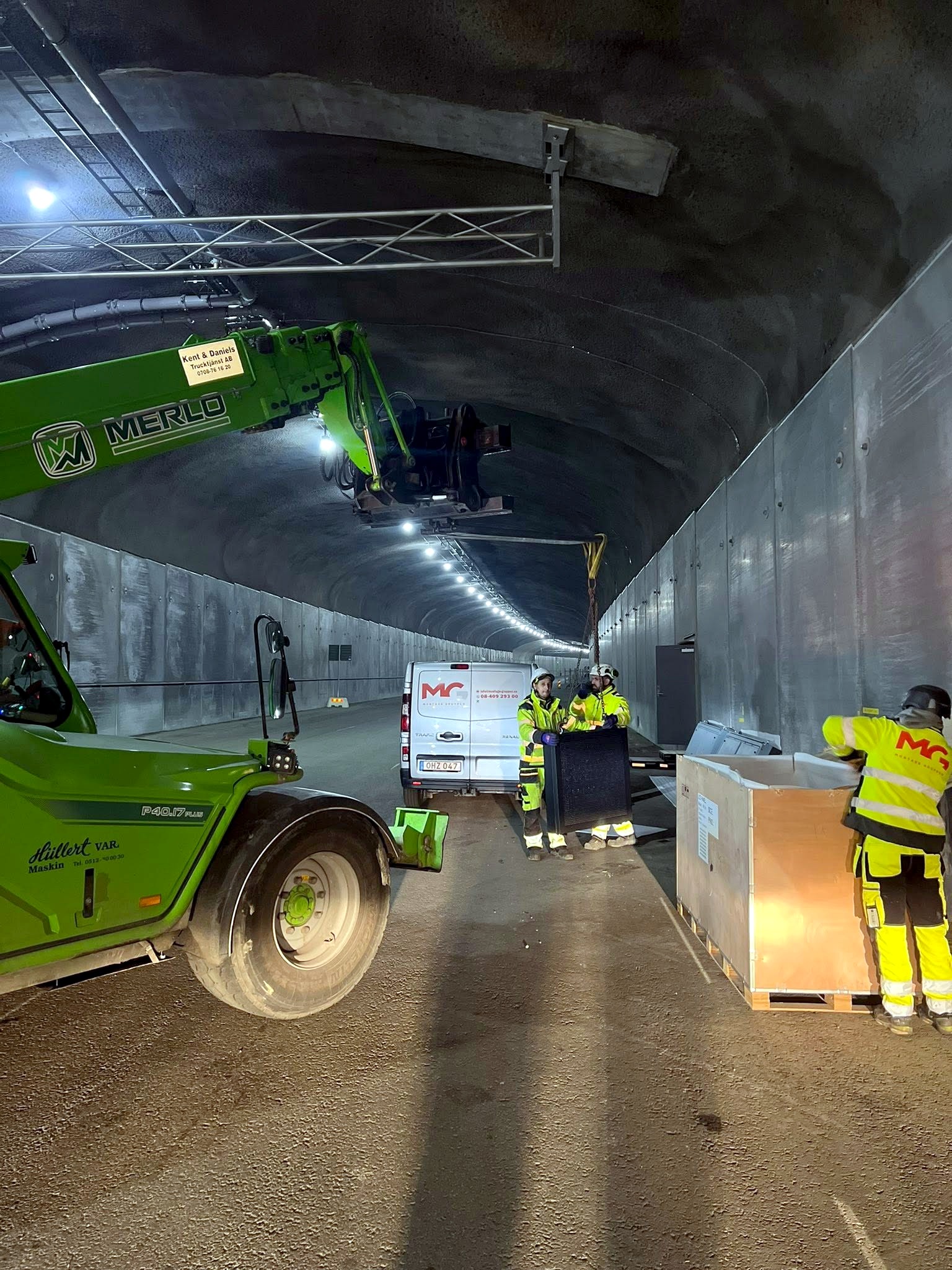 Montörer arbetar från lift i tunnel, Montagegruppens servicebil i bakgrunden